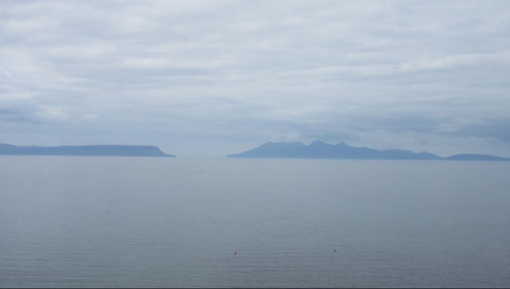 Color photograph of the Scottish Islands known as Eigg and Rùm taken on a cloudy day.